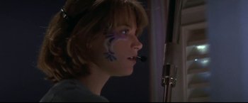 Movie still from “Point of No Return” (1993), directed by John Badham – A woman with a face paint is looking at a microphone; Close Up shot, Low angle