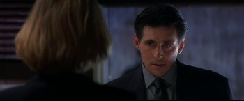 Movie still from “Point of No Return” (1993), directed by John Badham – A man in a suit and tie looking at a woman in a suit; Close Up shot, Over the shoulder angle