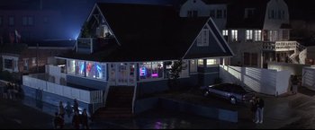 Movie still from “Point of No Return” (1993), directed by John Badham – A house with a car parked in front of it at night; Extreme Wide shot, High angle