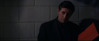 Movie still from “Point of No Return” (1993), directed by John Badham – A man in a suit and tie standing in front of a brick wall; Close Up shot, Low angle