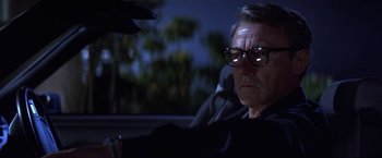 Movie still from “Point of No Return” (1993), directed by John Badham – A man with glasses sitting in the back of a car at night; Close Up shot, Low angle