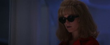 Movie still from “Point of No Return” (1993), directed by John Badham – A woman with blonde hair wearing sunglasses and a red jacket; Close Up shot, Low angle