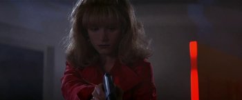 Movie still from “Point of No Return” (1993), directed by John Badham – A woman holding a cell phone while wearing a red jacket; Close Up shot, Low angle