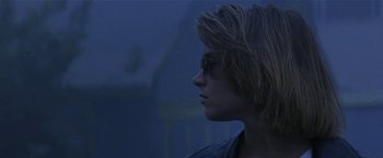 Movie still from “Point of No Return” (1993), directed by John Badham – A young woman with sunglasses is looking out a window; Close Up shot, Low angle