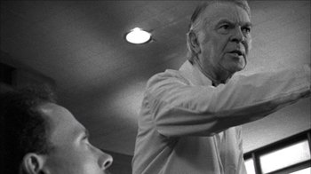 Movie still from “Poison” (1991), directed by Todd Haynes – An older man standing next to a younger man in a room; Close Up shot, Low angle