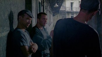 Movie still from “Poison” (1991), directed by Todd Haynes – A group of men standing next to each other on a street; Medium shot, Over the shoulder angle