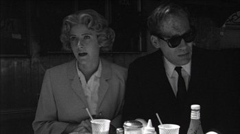Movie still from “Poison” (1991), directed by Todd Haynes – A man and a woman sitting at a table; Medium shot, Low angle