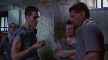 Movie still from “Poison” (1991), directed by Todd Haynes – A group of men standing next to each other in a room; Medium shot, Low angle