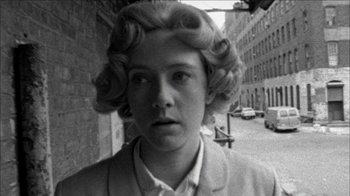 Movie still from “Poison” (1991), directed by Todd Haynes – A black and white photo of a woman in a suit; Close Up shot, Over the shoulder angle
