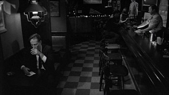 Movie still from “Poison” (1991), directed by Todd Haynes – People sitting at a table in an empty restaurant; Wide shot, High angle