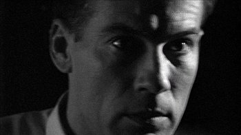 Movie still from “Poison” (1991), directed by Todd Haynes – A man's face in black - and - white; Extreme Close Up shot, Low angle