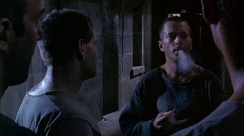 Movie still from “Poison” (1991), directed by Todd Haynes – A man smoking a cigarette while talking to another man; Medium shot, Over the shoulder angle