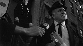 Movie still from “Poison” (1991), directed by Todd Haynes – A man in a suit and hat is being interviewed by a reporter; Close Up shot, Low angle