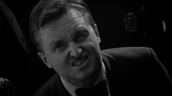 Movie still from “Poison” (1991), directed by Todd Haynes – A man in a suit and a bow tie is smiling for the camera; Close Up shot, High angle