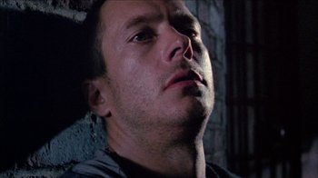 Movie still from “Poison” (1991), directed by Todd Haynes – A man's face in a dark room; Close Up shot, Low angle