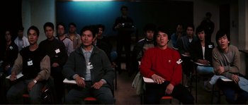 Movie still from “Police Story” (1985), directed by Jackie Chan – A group of people sitting in a room; Medium shot, High angle