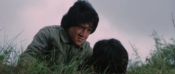 Movie still from “Police Story” (1985), directed by Jackie Chan – A man with long black hair is looking at another man with long black hair; Close Up shot, Low angle
