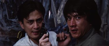 Movie still from “Police Story” (1985), directed by Jackie Chan – Two men are holding guns and posing for a picture; Close Up shot, Low angle