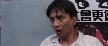 Movie still from “Police Story” (1985), directed by Jackie Chan – A person wearing a white shirt; Close Up shot, High angle