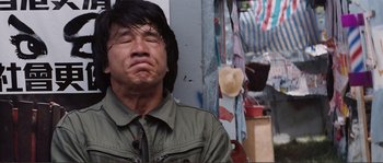Movie still from “Police Story” (1985), directed by Jackie Chan – A man with long black hair is crying; Close Up shot, Low angle