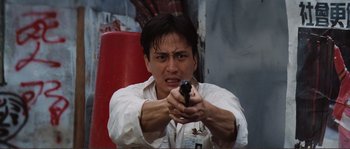 Movie still from “Police Story” (1985), directed by Jackie Chan – A man holding a gun while wearing a white shirt; Close Up shot, Low angle