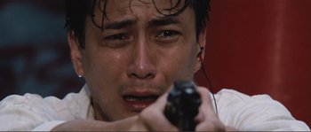 Movie still from “Police Story” (1985), directed by Jackie Chan – A person holding a gun; Close Up shot, Low angle