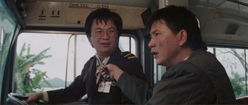 Movie still from “Police Story” (1985), directed by Jackie Chan – Two asian men are talking on a train; Close Up shot, Over the shoulder angle