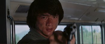 Movie still from “Police Story” (1985), directed by Jackie Chan – A man with a gun in his hand; Close Up shot, Low angle