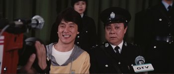 Movie still from “Police Story” (1985), directed by Jackie Chan – A man and a woman in uniform smiling for the camera; Close Up shot, Low angle