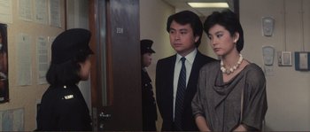 Movie still from “Police Story” (1985), directed by Jackie Chan – A man and a woman standing next to each other in a hallway; Medium shot, Over the shoulder angle