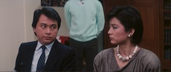 Movie still from “Police Story” (1985), directed by Jackie Chan – A man and a woman sitting next to each other; Close Up shot, Over the shoulder angle
