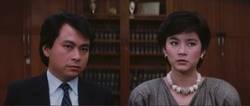 Movie still from “Police Story” (1985), directed by Jackie Chan – A man and a woman in front of a book case; Close Up shot, High angle