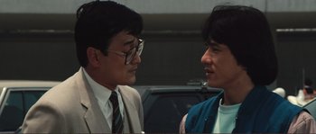 Movie still from “Police Story” (1985), directed by Jackie Chan – Two asian men talking to each other in a parking lot; Close Up shot, Over the shoulder angle