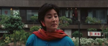 Movie still from “Police Story” (1985), directed by Jackie Chan – A woman wearing a blue jacket and a red scarf; Close Up shot, Low angle