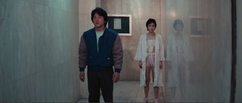 Movie still from “Police Story” (1985), directed by Jackie Chan – A man and a woman standing next to each other; Wide shot, Low angle