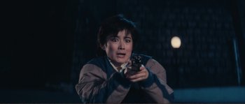 Movie still from “Police Story” (1985), directed by Jackie Chan – A woman holding a cell phone in her hands; Medium shot, High angle