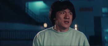 Movie still from “Police Story” (1985), directed by Jackie Chan – A person wearing a green shirt; Close Up shot, Low angle