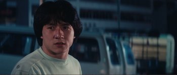Movie still from “Police Story” (1985), directed by Jackie Chan – A young man standing in front of a truck; Close Up shot, Low angle