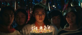 Movie still from “Police Story” (1985), directed by Jackie Chan – A girl with a birthday cake with lit candles; Close Up shot, Over the shoulder angle