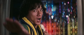 Movie still from “Police Story” (1985), directed by Jackie Chan – A man holding a banana in front of a colorful background; Close Up shot, Low angle