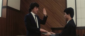 Movie still from “Police Story” (1985), directed by Jackie Chan – A man in a suit is being sworn in; Medium shot, Low angle