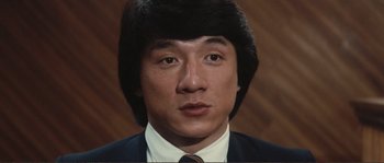 Movie still from “Police Story” (1985), directed by Jackie Chan – A person wearing a suit and tie; Close Up shot, Low angle