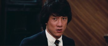 Movie still from “Police Story” (1985), directed by Jackie Chan – A person wearing a suit and tie; Close Up shot, Low angle