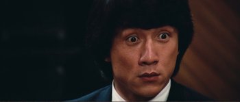 Movie still from “Police Story” (1985), directed by Jackie Chan – A person wearing a suit and tie; Close Up shot, Low angle