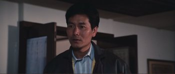 Movie still from “Police Story” (1985), directed by Jackie Chan – A person wearing a suit and tie; Close Up shot, Low angle