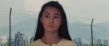 Movie still from “Police Story” (1985), directed by Jackie Chan – A woman with long black hair wearing a yellow shirt; Close Up shot, High angle