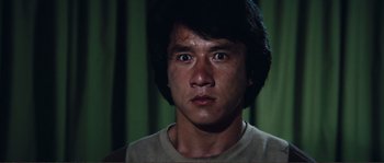 Movie still from “Police Story” (1985), directed by Jackie Chan – A person looking at the camera; Close Up shot, Low angle