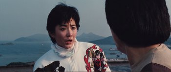 Movie still from “Police Story” (1985), directed by Jackie Chan – A woman in a white jacket is talking to a man; Close Up shot, Over the shoulder angle