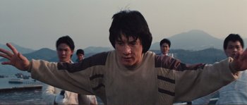 Movie still from “Police Story” (1985), directed by Jackie Chan – A group of young men standing next to each other on top of a hill; Medium shot, Low angle
