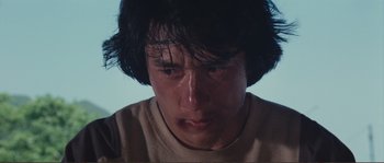 Movie still from “Police Story” (1985), directed by Jackie Chan – A person's face with water coming out of his eyes; Close Up shot, Low angle